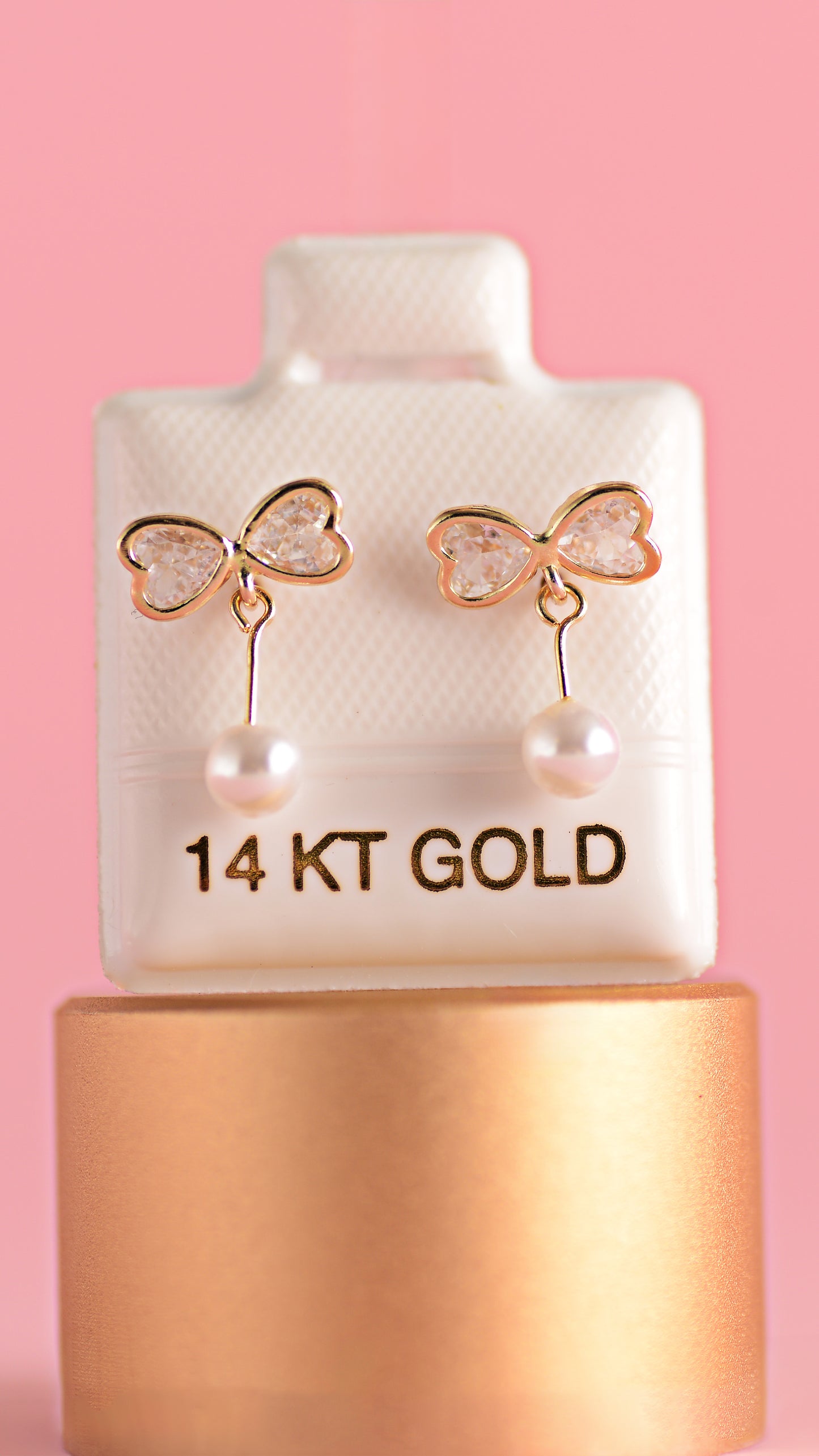 Aretitos de moñito con zirconias y perla en oro amarillo de 14K.